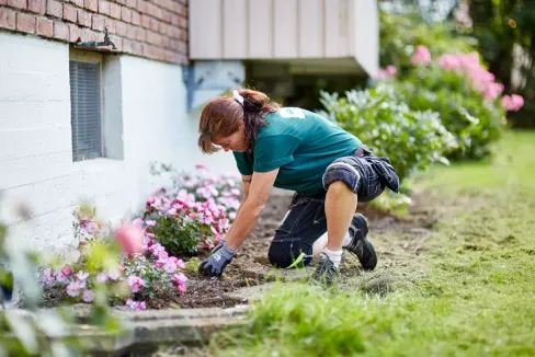 Gartner som jobber med et blomsterbed for en boligblokk